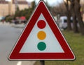 A road sign that indicates a traffic light intersection with a blurred background