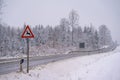 Road sign indicating deer and animals crossing in snow next to rural road Royalty Free Stock Photo