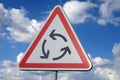 Road sign indicating a roundabout in close-up on the background of the sky with clouds Royalty Free Stock Photo