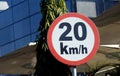 A road sign of 20 KMH twenty Kilometers per hour speed limit in the slow lane near gateway, restaurants and cafes, Prohibitory