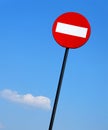 Road sign on a metal pole `Do not enter` sign against a blue sky with white clouds background.