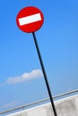 Road sign on a metal pole `Do not enter` sign against a blue sky with white clouds background.