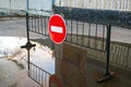 Road sign No entry for vehicular traffic on metal stand in puddle near building