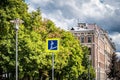 Road sign pedestrian underpass on the background of the cityscape. Street lights, yellow-green leaves of trees and thunderstorm Royalty Free Stock Photo