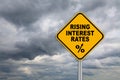 Road sign rising interest rates with dark cloud background.