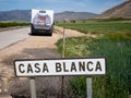 A road sign says the name of a village `Casa Blanca` in a remote Spanish valley. A motorhome is parked in the background with