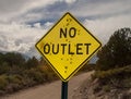 A road sign stating No Outlet riddled with bullet holes in the country