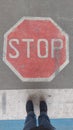 Road sign `Stop` painted on road with two standing feet in front