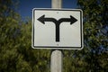 Road sign on a street pole with arrows pointed in opposite directions facing east and west