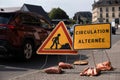 Road sign weighted with sandbags indicating alternating traffic due to road works Royalty Free Stock Photo