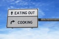 Road sign with words eating out versus cooking. White two street signs with arrow on metal pole. Directional road, Crossroads Road