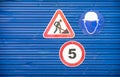 Road signs against a blue metal fence