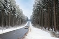 Road through a snow covered forest, slippery and frosty street in winter, empty highway in cold temperature, seasonal weather Royalty Free Stock Photo