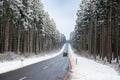 Road through a snow covered forest, slippery and frosty street in winter, empty highway in cold temperature, seasonal weather and Royalty Free Stock Photo