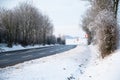 Road through a snow covered forest, slippery and frosty street in winter, empty highway in cold temperature, seasonal weather and Royalty Free Stock Photo