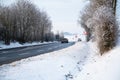 Road through a snow covered forest, slippery and frosty street in winter, empty highway in cold temperature, seasonal weather Royalty Free Stock Photo