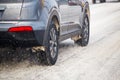 Road snow pieces flow from wheels of dirty car accelerating in daylight city with selective focus Royalty Free Stock Photo