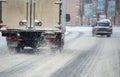 Road snow pieces flow from wheels of dirty truck moving fast in daylight city with selective focus.