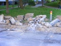 Road street repair, heaps of curdstones lying on the sidewalk near the pit for installing a border. Broken asphalt surface on othe