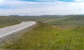 The road stretches into the distance on a background of green meadow Royalty Free Stock Photo