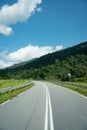 Road and summer mountain range landscape with green grass forest, blue sky, natural outdoors travel background, cloudy day, asphal Royalty Free Stock Photo