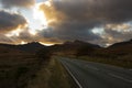 A4086 road, at sunset, heading towards the Llanberis Pass with mount Snowdon in the distance.