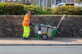 09/15/2020 Ryde, Isle of Wight, UK A road sweeper in high visibility clothing pushing his dust cart with brooms in it