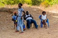 Unidentified local three people sit in chairs and one woman sta