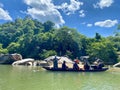 Sightseeing boating on the river with tranquil natural scene with blue mountains, blue sky, and scattered rocks o Royalty Free Stock Photo