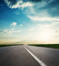 Road to horizon in sunset. Low clouds with sun over asphalt Royalty Free Stock Photo