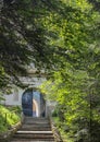 The road to the monastery in the forest. Stairs, gates, trees in sunlight. Forgotten church in the woods near the road Royalty Free Stock Photo
