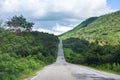 Road to mountain / A long straight road leading towards a nature green tree on the mountains Asphalt road in Thailand Royalty Free Stock Photo