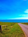 Road to nowhere in Tasmania green grass ocean views blue sky Royalty Free Stock Photo