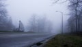 the road with the traffic lights is foggy at night