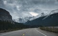 Road trip with car driving on highway with rocky mountains and gloomy sky in Banff national park Royalty Free Stock Photo