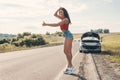 Road trip, transport, travel, gesture and people concept - happy young women with broken car showing hitchhiking gesture Royalty Free Stock Photo