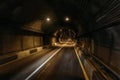 Road tunnel in mountain illuminated by lamps