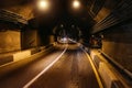 Road tunnel in mountain illuminated by lamps