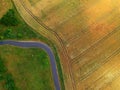 Road turn between wheat fields and gree meadow with trees, aerial view Royalty Free Stock Photo