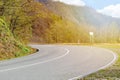 The road turns to the left among the small mountains and forests illuminated by the sun light.