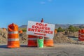 Road under construction with golf course entrance sign and traffic barrels Royalty Free Stock Photo