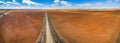 Road vanishing into the horizon between plowed fields.