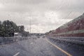 Road view through windshield car window with going rain drops during driving at speed. Unfocused highway. Autumn. Royalty Free Stock Photo