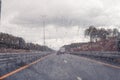 Road view through windshield car window with going rain drops during driving at speed. Unfocused highway. Autumn. Royalty Free Stock Photo