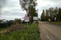 The road in the village before the rain. Traffic sign `Slippery road`. Royalty Free Stock Photo