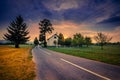 Road beside wheat field and cottage at sunset with colorful overcast sky.. Royalty Free Stock Photo