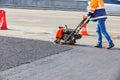 A road worker compacts asphalt with a petrol vibratory plate compactor