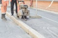 Road worker cutting asphalt road, working on the road reconstruction.