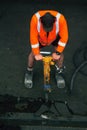 Road worker with a drill breaking up asphalt on the road