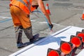 A road worker paints with an airbrush a white road marking of a pedestrian crossing on a fenced section of the roadway on a sunny Royalty Free Stock Photo